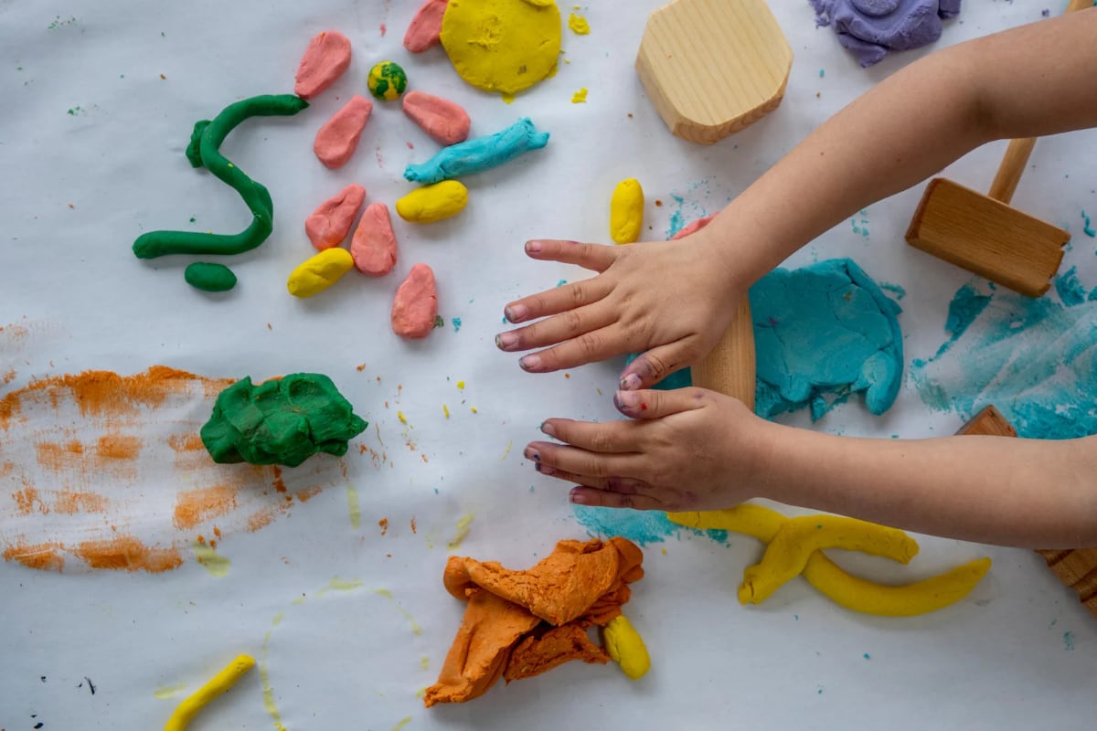 A young child shaping colorful clay creations by hand